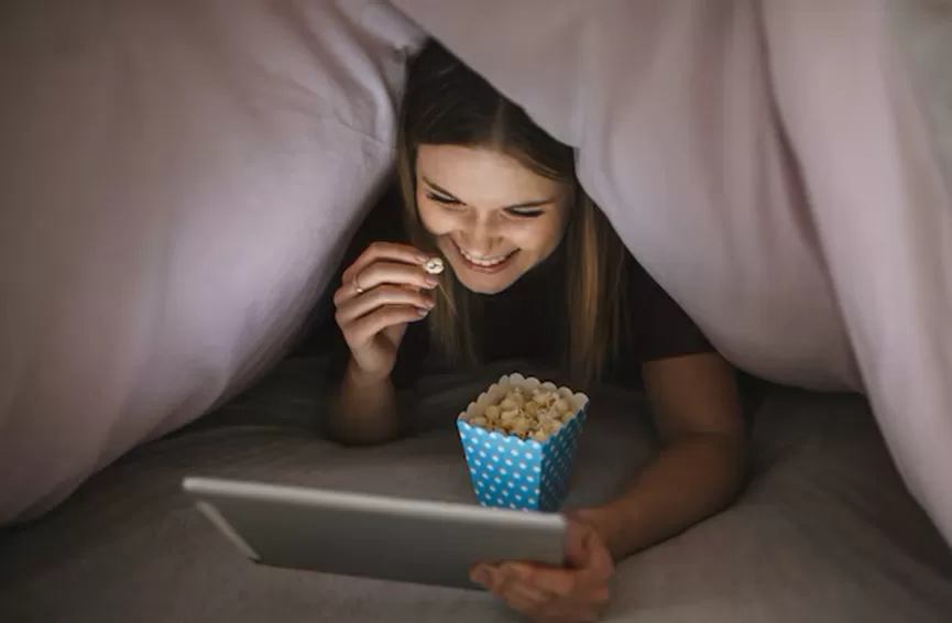 cheerful-woman-watching-film-blanket