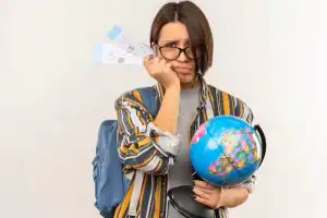 unpleased-young-student-girl-wearing-glasses-back-bag-holding-airplane-tickets-globe-isolated-white-background-with-copy-space