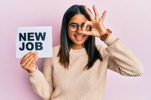 young-latin-girl-holding-new-job-message-paper-smiling-happy-doing-ok-sign-with-hand-eye-looking-through-fingers