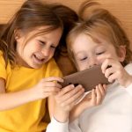 top-view-young-kids-using-smartphone-together
