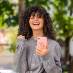 caucasian-woman-use-mobile-smartphone-celebrating-win-good-message-news-outdoors-city-street