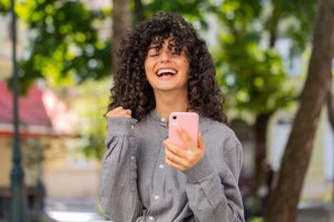 caucasian-woman-use-mobile-smartphone-celebrating-win-good-message-news-outdoors-city-street