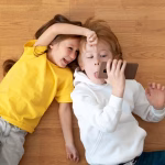 flat-lay-smiley-kids-using-smartphone-together