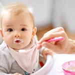 father-feeding-baby-sitting-highchair-home