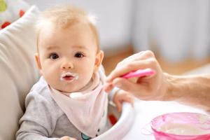 father-feeding-baby-sitting-highchair-home
