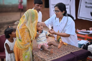 In a rural health care camp, a picture captures a crucial moment as a female doctor administers polio dosage to a child. The image highlights the efforts of medical professionals in preventing the spread of polio and protecting the health of young children in rural communities.